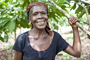 Akua Krampa, a 58-year old cocoa farmer in Ghana, standing next to a cocoa tree. Photo credit: CARE